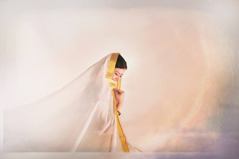Woman in a white and gold sari, veiled
